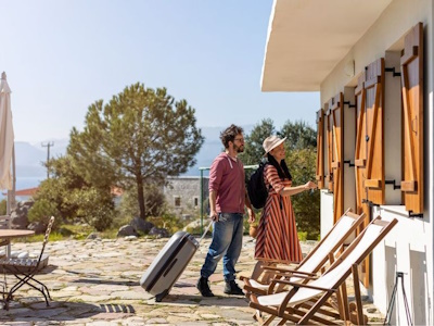 Couple avec bagages arrivant devant leur maison